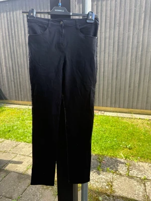 Svarta jeans dam - Snygga svarta jeans med klassisk femficksdesign och raka ben. Jeansen har bälteshällor och knappstängning framtill. Perfekta för en stilren och enkel look.