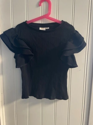 Svart tröja med volanger från Gina tricot - Säljer en tröja från Gina tricot i storlek 146-152. Endast använd fåtal gånger. Kontakta om du är intresserad