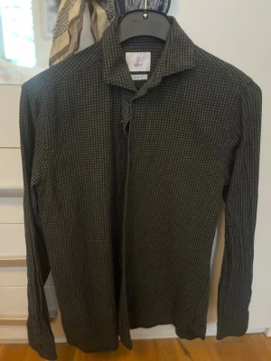 Rutig svart skjorta från Bläck - Snygg svart/grön skjorta från Bläck med diskret rutigt mönster. Skjortan har klassisk krage, långa ärmar och knäppning framtill. Perfekt för dig som gillar stilrena plagg med lite edge. Skick 10/10 NEVER WORN.