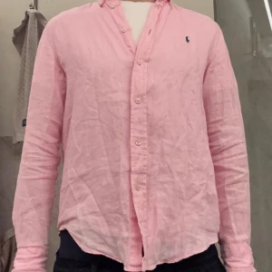Rosa linneskjorta från Ralph Lauren - Säljer en ljusrosa skjorta från Ralph Lauren i linne. Skjortan har klassisk krage, knappar framtill och den ikoniska loggan broderad på bröstet. Skjortan är i stlk 14-16 som passar XS. Skjortan är i bra skick. Hör av er vid frågor!🙌