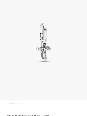 Pandora korsberlock i silver - Stilren berlock från Pandora i form av ett kors, tillverkad i silver med små gnistrande stenar på framsidan. Perfekt att hänga på ett halsband eller armband för en personlig touch. Klassisk design med modern känsla.