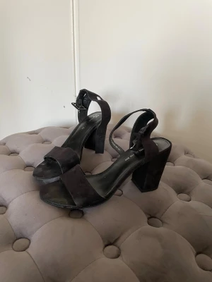 Svarta vanliga klackar - Snygga svarta klackar med bred klack och öppen tå. Skorna har en justerbar ankelrem. Perfekta för dig som gillar en trendig och stabil klack. 