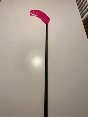 Innebandyklubba salming svart/rosa - Säljer en innebandyklubba från salming klubbahustes egna, med svart skaft och ett coolt rosa blad. Klubban har en sportig design och är perfekt för dig som gillar innebandy. Bladet är i nytt skick och det är samma med klubban. Den har inge Linda på. 92 cm lång. 