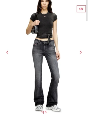 Svarta bootcut jeans från Diesel - Snygga mörkgråa bootcut jeans från Diesel industry med lätt tvättad look och klassiska fem fickor. Jeansen har låg midja och utsvängda ben, perfekt för en trendig och avslappnad stil. Materialet är denim med stretch för extra komfort.