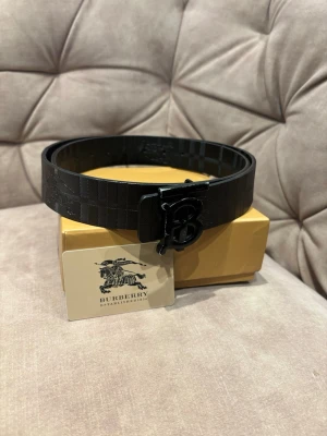 Svart bälte med rutigt mönster - Svart 115cm bälte 