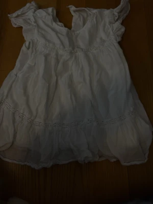 Vit romantisk blus med volanger - Säljer eftersom jag har växt ur den. Söt vit blus med volangdetaljer och rynkade partier. Blusen har korta ärmar med resår och en luftig, flowy passform. Perfekt för en somrig look och lätt att matcha med jeans eller kjol. Materialet känns tunt och mjukt, troligen bomull eller linne.