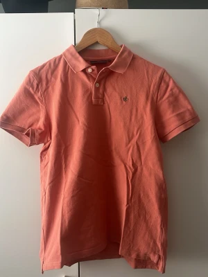Morris pike - Säljer en snygg korallfärgad pikétröja från Stenströms med klassisk krage och två knappar framtill. Tröjan har korta ärmar och en liten broderad logga på bröstet. Perfekt till jeans eller shorts för en avslappnad look. Nästan HELT ny