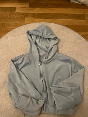Ljusblå hoodie från H&M Divided - Mysig ljusblå hoodie från H&M Divided med dragkedja framtill och stor huva. Tillverkad i mjukt material som känns skönt mot huden. Perfekt för chill dagar och enkel att matcha med jeans eller mjukisbyxor.
