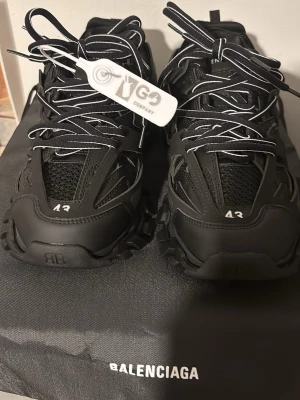 Balenciaga track - Säljer ett par svarta Balenciaga sneakers med chunky sula och detaljer i mesh och syntet. Skorna har vita kontrastsömmar och snörning med reflekterande inslag. Balenciaga-logga på sidan ger en exklusiv vibe. Perfekta för dig som gillar statement sneakers.