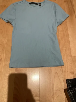 Ljusblå t-shirt från vero moda - Säljer en ljusblå ribbad t-shirt från Zara i storlek XS. T-shirten har rund halsringning och korta ärmar. Enkel och stilren modell som passar perfekt till jeans eller kjol.