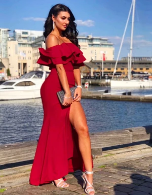 Vinröd offshoulder långklänning - Vinröd långklänning med offshoulder och volang upptill. Klänningen har en slits på ena sidan och figurnära passform. Perfekt för bal eller fest. Materialet känns mjukt och följsamt. Använd endast en gång. Köpte för 5000