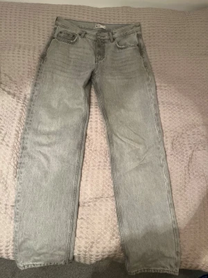 Low waist grå jeans från Gina Tricot - Säljer ett par ljusgrå jeans från Gina Tricot i storlek 36. Modellen har klassisk design, raka ben och normal passform. Jeansen har knapp och dragkedja framtill. Perfekt för dig som gillar enkel och clean stil.
