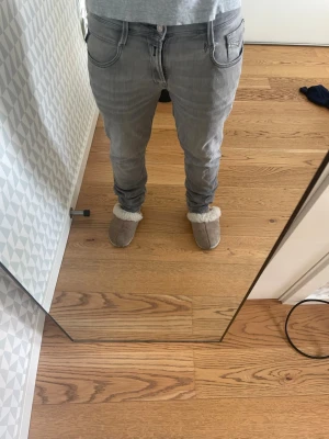 Replay anbass - Säljer ett par grå slim fit jeans med klassisk femficksdesign och dragkedjegylf. Jeansen har en snygg tvättad look och passar perfekt till en avslappnad stil. Materialet är mjukt och stretchigt för extra komfort. Hål vi skrivet men lagat syns inte så mycket när man har på sig dem, storlek 30/30