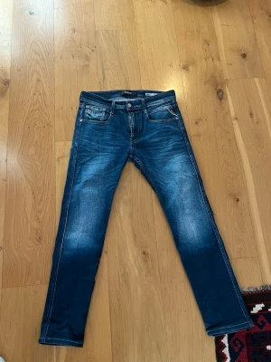 Blå slim fit jeans från Replay - Säljer ett par snygga blå slim fit jeans från Replay, modell Anbass. Jeansen har slitningar framtill. Perfekta för dig som gillar en modern stil.