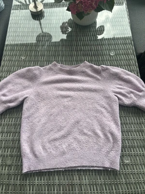 Ljuslila stickad tröja med puffärm - Supersöt ljuslila stickad tröja med puffärmar och ribbade muddar vid ärmslut och nederkant. Tröjan är från vero moda stl S