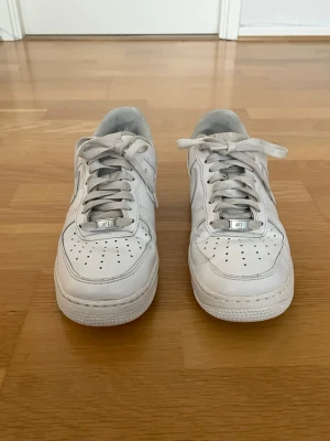 Nike Air Force 1 White – Storlek 41 - Säljer ett par vita Nike Air Force 1 i storlek 41. Skorna är använda men i bra skick och har mycket kvar att ge. De klassiska vita Air Force 1 passar till det mesta och är alltid ett säkert val i garderoben. Normalt slitage finns i form av mindre veck på ovandelen och viss smuts på skosnören och sula, men inga större skador. Lite slitage finns inuti skon men inte alls mycket (se bild för egen bedömning). Men fortfarande skorna är generellt i bra skick.