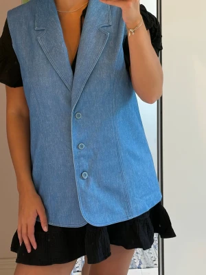 Denimväst med knappar - Rak passform och är tillverkad i denimliknande tyg. Köpt second hand och därför har den tyvärr varken etikett för storlek eller material. Men den är oversized på mig som är storlek M. 