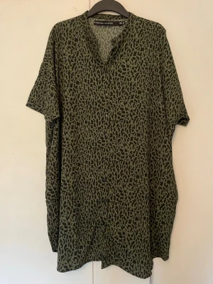 Grön leopardmönstrad kortklänning - Säljer en grön kortklänning från Lager 157 med leopardmönster. Klänningen har v-ringning, korta ärmar och en loose passform. Perfekt för dig som gillar djurmönstrat och vill ha en avslappnad stil.