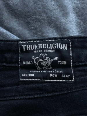 True Religion W26 - Säljer ett par svarta bootcut jeans från True Religion i storleken W26💕Superfint skick förutom lite slitningar bak längst ner (se sista bild)! Köpta på plick men säljes då de är för stora för mig i midjan och jag därför inte använder dem🙈         MÅTT: Midja= 39cm från ena sidan till den andra            Innerbens längd= 81 cm                                   Jag är ca 170 cm lång och de går ner till golvet på mig, skriv till mig om du har några frågor! Nypris är 1,299kr💗