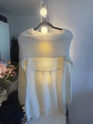 Vit off shoulder stickad tröja - Säljer en vit stickad tröja med bred off shoulder-krage och långa ärmar. Tröjan har en lös och avslappnad passform med ribbstickade detaljer. Perfekt för dig som gillar en stilren och mysig look.