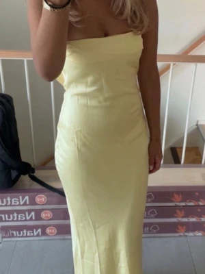 Ljusgul långklänning från Babyboo - Säljer en ljusgul långklänning från Babyboo med axelbandslös design och figurnära passform. Klänningen har en enkel, elegant look och är tillverkad i ett mjukt, glansigt material som ger en lyxig känsla. Perfekt för sommarens alla tillfällen! går att diskutera pris💗💗