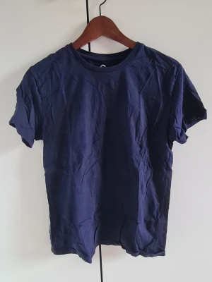 Mörkblå basic t-shirt i bomull - En enkel och stilren mörkblå t-shirt i mjuk bomull. Klassisk rund halsringning och korta ärmar. Perfekt till jeans eller shorts för en clean look.