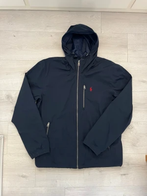 Ralph lauren vindjacka mörkblå - Säljer en stilren och lätt vindjacka från Ralph Lauren i mörkblå färg. Perfekt jacka för sommaren, svala kvällar och dagar när vädret skiftar.  • Storlek: M • Färg: Mörkblå • Skick: Mycket fint skick • Lätt och bekväm att bära • Klassisk och tidlös design • Perfekt till sommaren, våren och tidig höst • Enkel att matcha med jeans, shorts eller chinos