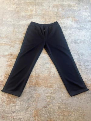 Svarta mjukisbyxor från Fred Perry - Säljer ett par svarta mjukisbyxor från Fred Perry i storlek L. Byxorna har raka ben, elastisk midja med dragsko samt en bakficka med den klassiska Fred Perry-loggan.  Tillverkade i ett mjukt och stretchigt material som ger en bekväm passform och hög komfort. Passar lika bra för avslappnade dagar hemma som för en stilren vardagslook.  Byxorna är i fint skick och pris kan diskuteras vid seriöst intresse. Hör gärna av dig om du har några frågor!