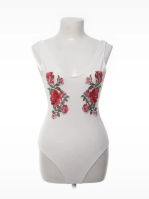 Vit body med rosbroderi - Snygg vit body med djup urringning både fram och bak. Framsidan är dekorerad med broderade röda rosor och gröna blad, vilket ger en romantisk och trendig look. Tillverkad i stretchigt material för en bekväm passform. Perfekt att styla med jeans eller kjol. Köpte på Sellpy och bilderna är därifrån men det är alltså exakt denna som är på bilderna, har bara inte tagit nya!!
