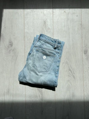Ljusblå jeans från Abrand Jeans - Säljer ett par ljusblå jeans från Abrand Jeans med klassisk femficksmodell och raka ben. Jeansen har en snygg vintage tvätt och är tillverkade i bomull. Perfekta för en avslappnad och trendig look. Raka högmidjade. Passar xs