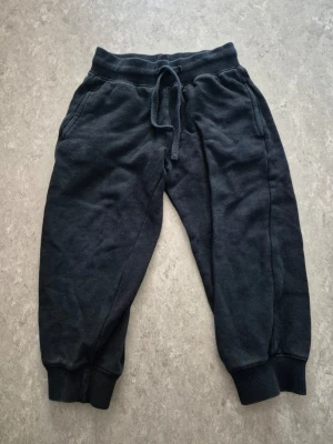 Mjukisbyxor - Svarta mjukisbyxor med resår i midjan och dragsko för skön passform. Byxorna har ribbade muddar vid bensluten och två sidofickor. Tillverkade i mjukt och bekvämt material, perfekta för chill dagar. Finns hål.