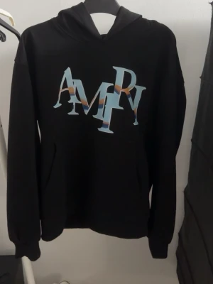 Svart hoodie från Amiri med tryck - Snygg svart hoodie från Amiri med stor färgglad AMIRI-logga på bröstet. 