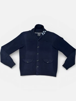 Woolrich cardigan - Snygg mörkblå kofta från woolrich med knäppning framtill, två fickor med lock och en liten bröstficka. Koftan har ribbade muddar och en hög krage med randig detalj på insidan. Perfekt för en stilren och avslappnad look.
