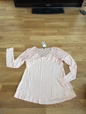 Ljusrosa topp med spetsdetaljer - Helt ny rosa topp med spetsdetaljer på axlar och ärmar. Köptes för 179 kr.  Från Cubus i storlek 158/164