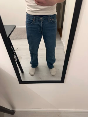 Levi's 501 blå raka jeans - Klassiska blå Levi's 501 jeans med rak passform och fem fickor. Jeansen har knappgylf och är tillverkade i slitstark denim. Perfekta för en avslappnad och tidlös stil.