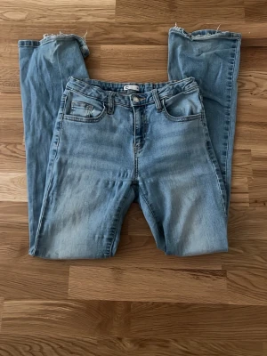 Ljusblå raka jeans från Cubus - Säljer ett par ljusblå jeans från Cubus med bootcut ben och råa, benen har gått sönder lite pågrund av att de är för långa. Klassisk femficksmodell och snygg tvättad look. Perfekta för en avslappnad och trendig stil. Materialet är mjukt och relativt stretchig denim som sitter skönt hela dagen.