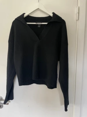 Svart stickad tröja - Säljer denna svarta tröja som har krage, har ändå använts en del så det finns tecken på det (lite nopprar finns på sidorna). Lite kortare i modellen.