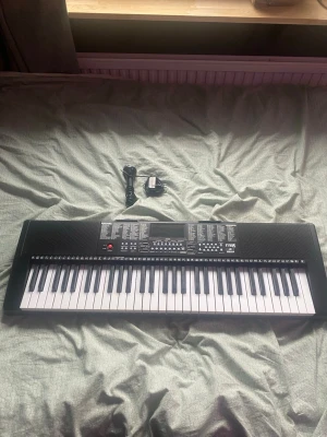 Svart och vit digital keyboard - Elektroniskt keyboard i svart och vitt med 61 tangenter, många olika ljud och funktioner. Medföljer strömadapter och kabel. Perfekt för dig som vill spela musik hemma eller öva på nya låtar. Modern design med tydliga knappar och display.