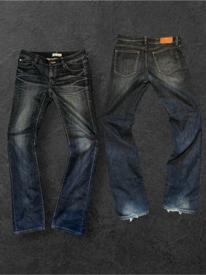 Selvedge jeans från Acne Studios - Snygga mörkblå jeans från Acne Jeans med klassisk femficksmodell och raka ben. Jeansen har slitningar och ljusare partier för en cool, använd look. Tillverkade i denim med kontrastsömmar och läderpatch bak i midjan.