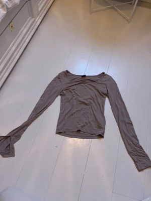 Beige långärmad topp med utsvängda ärmar - Trendig beige topp med långa, utsvängda ärmar och en mjuk, stretchig känsla. Toppen har en enkel, rundad halsringning och är tillverkad i ett tunt material som passar perfekt till olika outfits.