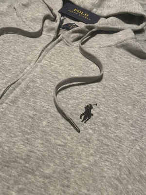 Grå Ralph Lauren zip hoodie - Säljer denna snygga Ralph Lauren hoodie med dragkedja på🔥Storlek M✅Skriv dm om frågor. Priset är inte hugget i sten🤝