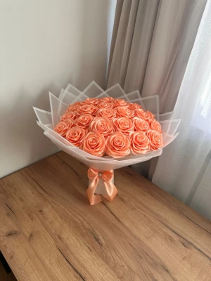 Bukett med konstgjorda rosor  - Säljer en exklusiv bukett med konstgjorda rosor i persikofärg, vackert arrangerade i lager av vit plastfolie och dekorerad . Perfekt som present eller dekoration till hemmet.