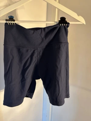 Mörkblå ribbade cykelshorts - Säljer ett par mörkblå cykelshorts med ribbad struktur och hög midja. Perfekta för träning eller chill dagar. Stretchigt material som sitter skönt och följer kroppen.