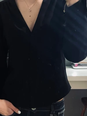 Svart v-ringad blus med knappar - Jättesöt svart blus med v-ringning och knappar framtill. Jättefint skick och inga defekter alls, storlek ZS från Monki. Går att matcha till allting.🤎