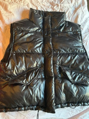 Svart glansig dunväst - Svart dunväst med glansig finish, storlek S från HM