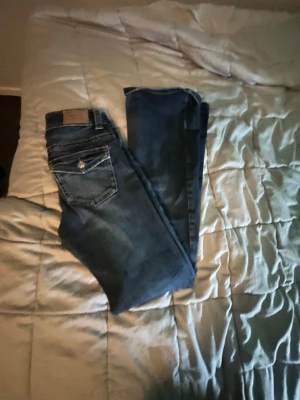 Blå bootcut jeans från Hollister - Snygga blå bootcut jeans från Gina tricot med klassisk femficksdesign och silverfärgade detaljer på fickorna. Jeansen har en låg midja och är tillverkade i mjukt denimtyg med lätt slitningar för en avslappnad look.