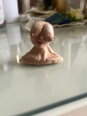 Handgjord miniskulptur av en abstrakt kvinna - Unik handgjord  mini skulptur av en kvinna med byst som ögon i beige lera. Skulpturen har ett abstrakt ansikte med markerade drag och en mjuk, ojämn yta. Perfekt som dekoration eller konstnärlig detalj till skrivbordet eller hyllan. Perfekt för de som gillar något lite bold!