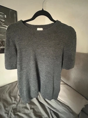 Grå stickad tröja med kort ärm - Mysig grå stickad tröja med korta ärmar och rund halsringning. Använd en gång. Storlek M men sitter mer som en S