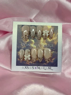 SoftLeo (M);Medium Almond - Snygga handgjorda press-on naglar i nude och brunt leopardmönster. Naglarna har en medium almondform och dekoreras med vita 3D-rosetter för extra wow-effekt. Perfekt för dig som vill ha trendiga och unika naglar utan att gå till salong.M: 16 mm, 12 mm, 12,5 mm, 11,5 mm, 10 mm