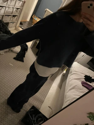 Mörkblå croppad stickad tröja - Säljer en mörkblå croppad stickad tröja med rund hals och långa ärmar. Tröjan har en avslappnad passform och är perfekt för lager-på-lager. Inget synligt märke på tröjan.